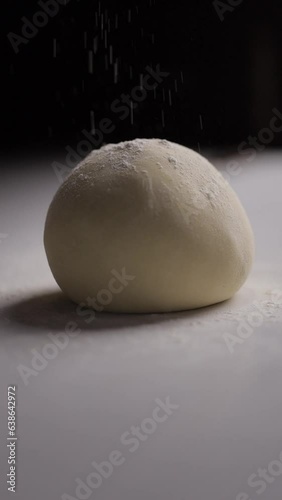 Man sprinkling flour over dough on wooden table. Homemade bakery