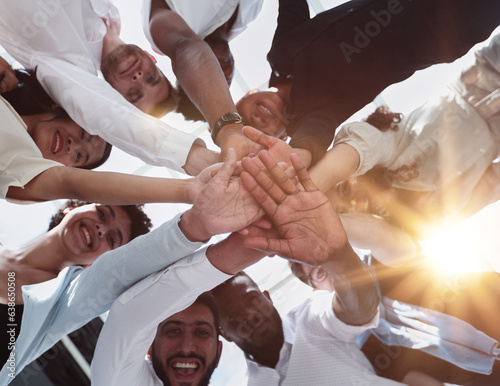 multinational business team looking down putting hands together