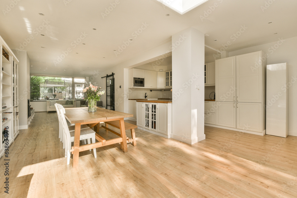 Fototapeta premium a kitchen and dining area in a house with wood floors, white cabinets and an open floor to the living room