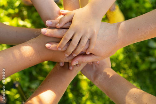 children holding hands standing on the green grass, the concept of friendship and a group of young people working in a team