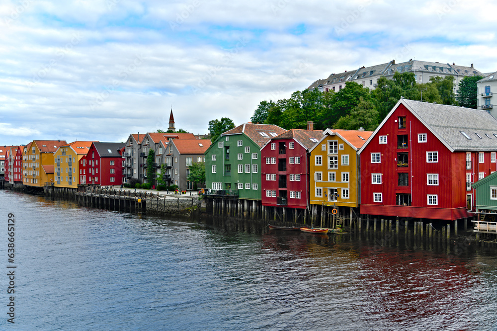 Historic old wooden buildings and houses with colorful facades over the river Nidelva in the Brygge district, in the scandinavian harbor town of Trondheim Norway
