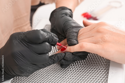 Professional manicurist working with client at table, closeup