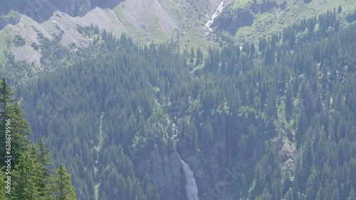 Staubifall Waterfall Amidst Dense Forest With Rocky Mountain Ridges At Background In The Canton Of Uri In Unterschachen, Switzerland. Tilt-up photo
