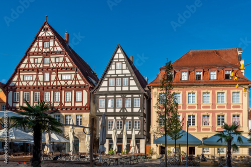 Häuserensemble von drei alten Patrizierhäusern am Marktplatz in der historischen Altstadt von Schwäbisch Gmünd mit Straßencafe im Vordergrund