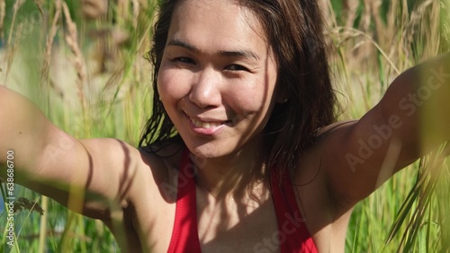 Portrait of a beautiful asian woman on the background of dry long grass while relaxing in summer. slow motion portrait. photo