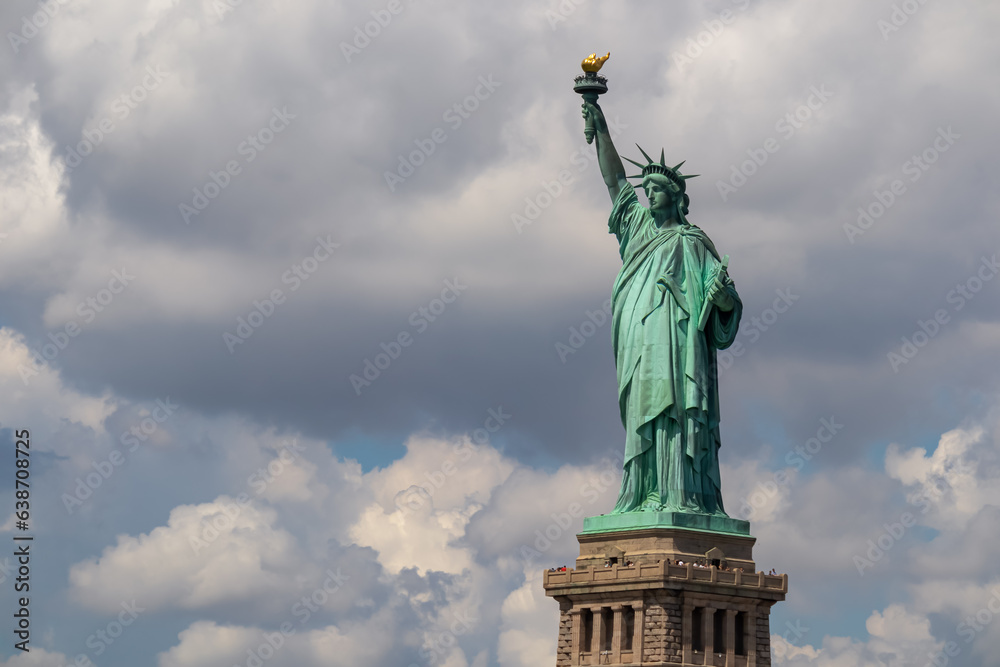 Iconic representation of freedom and independence, the Statue of Liberty with flaming torch on Liberty Island. The Lady on a Pedestal is surrounded by clouds. City landmark. American history.