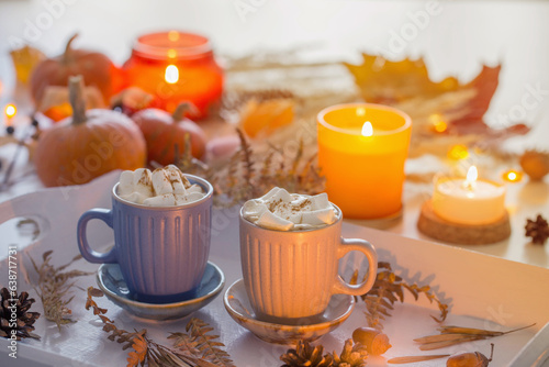 two cups of  coffee  with marshmallows  and autumn decor on white wooden tray