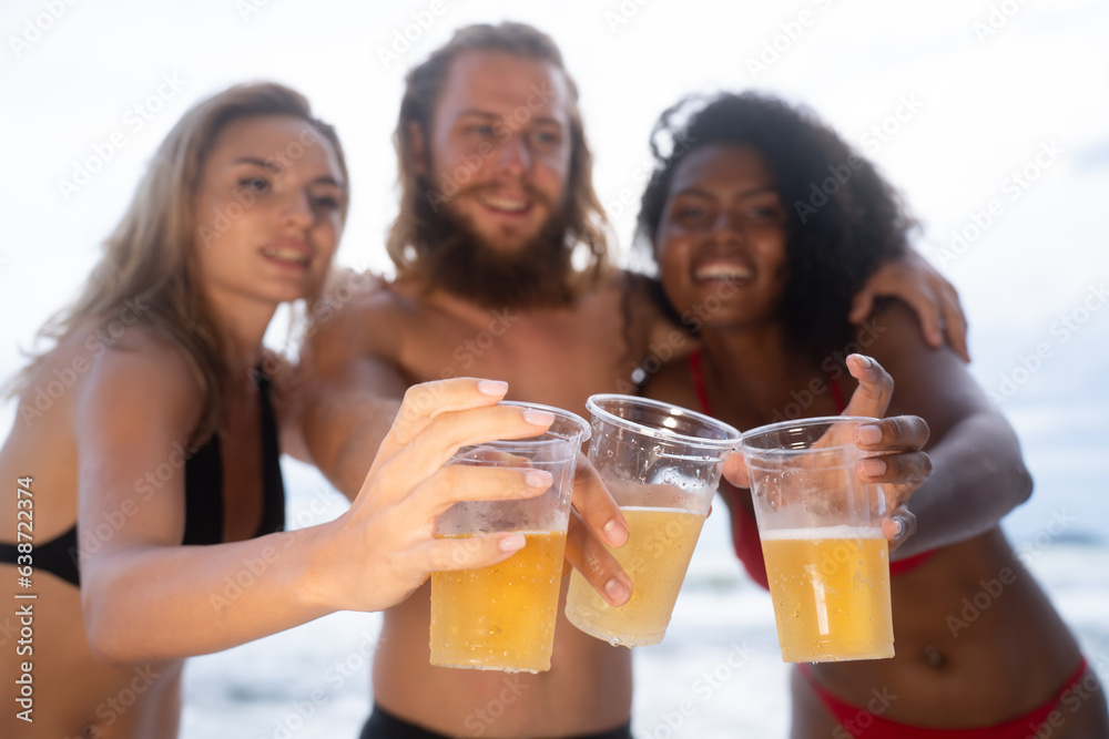 Multi-ethnic group of friends having fun on the beach, drinking beer and having fun Multi-ethnic group of friends having fun on the beach, drinking beer and having fun