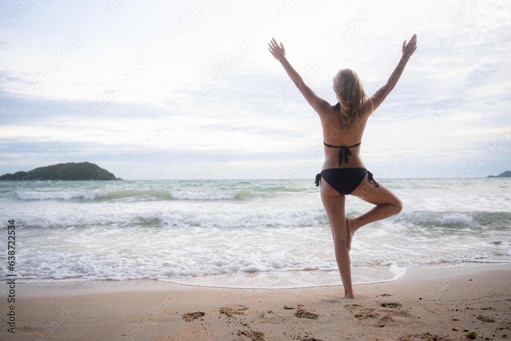 Young woman in black bikini practicing yoga on the beach at sunset. Young woman in black bikini practicing yoga on the beach at sunset.
