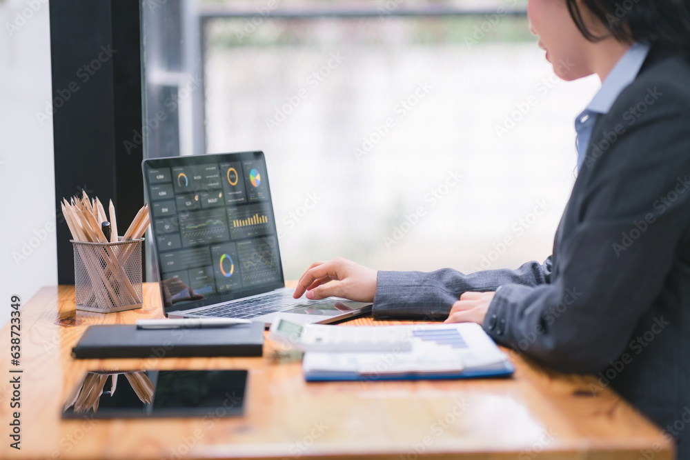 A businesswoman or accountant using laptop to analyze financial investments and business and marketing growth on a data graph. The concepts of accounting, economics, and commercial analysis. A businesswoman or accountant using laptop to analyze financial investments and business and marketing growth on a data graph. The concepts of accounting, economics, and commercial analysis.