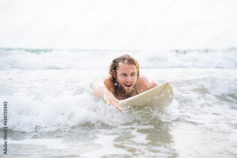 Young man surfing on the beach having fun and balancing on the surfboard Young man surfing on the beach having fun and balancing on the surfboard