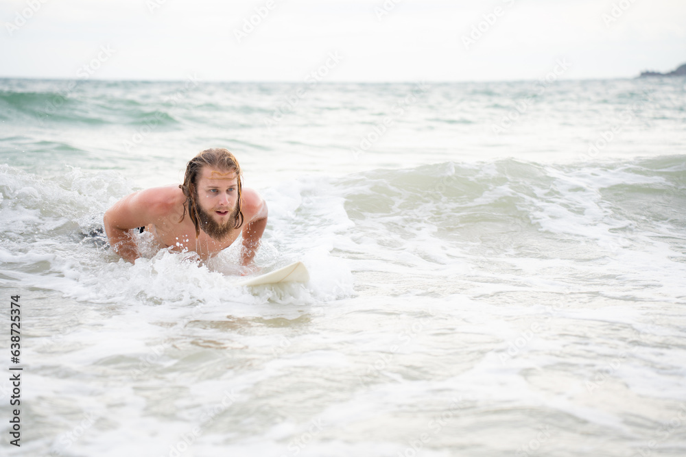 Young man surfing on the beach having fun and balancing on the surfboard