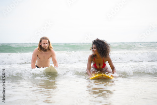 Young man and woman having fun with surfboard in the ocean on a sunny day © Wosunan