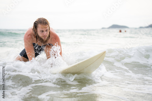 Young man surfing on the beach having fun and balancing on the surfboard © Wosunan