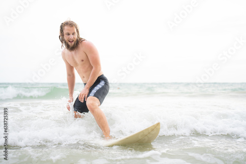Young man surfing on the beach having fun and balancing on the surfboard © Wosunan