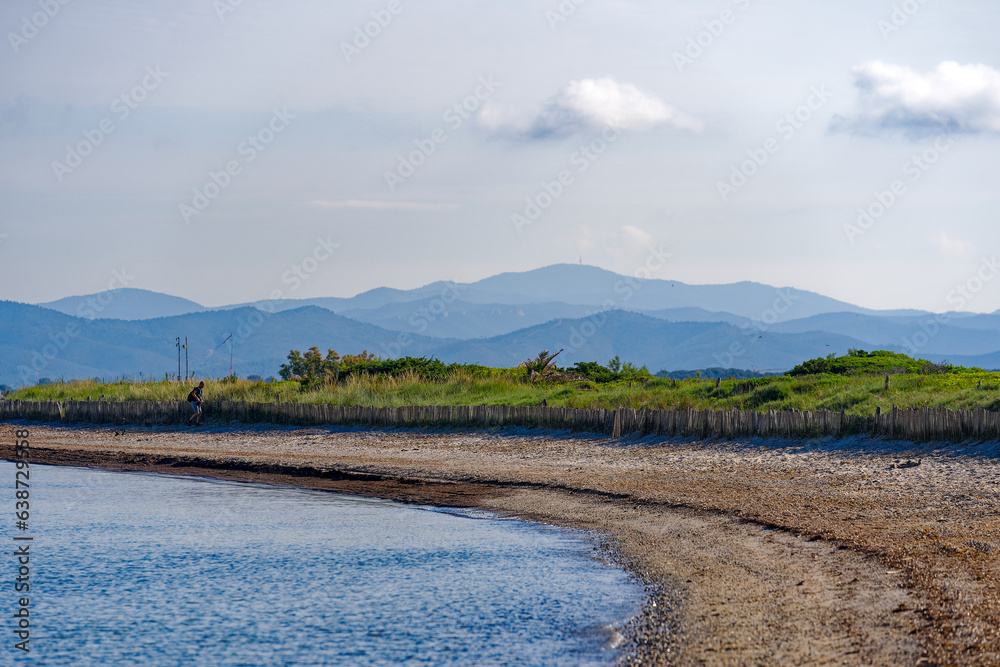 Scenic view of sandy beach with wooden fence on a blue cloudy evening at beach of Giens Peninsula. Photo taken June 8th, 2023, Giens, Hyères, France.