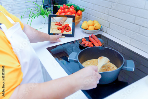 woman cooking by following the steps of a cooking tutorial on a tablet