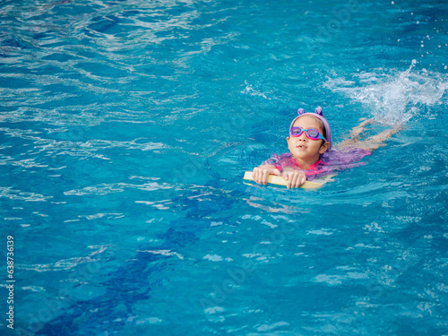 Asian child or kid girl wearing swimming suit to learning on swimming pool   learn and training swim on kick board