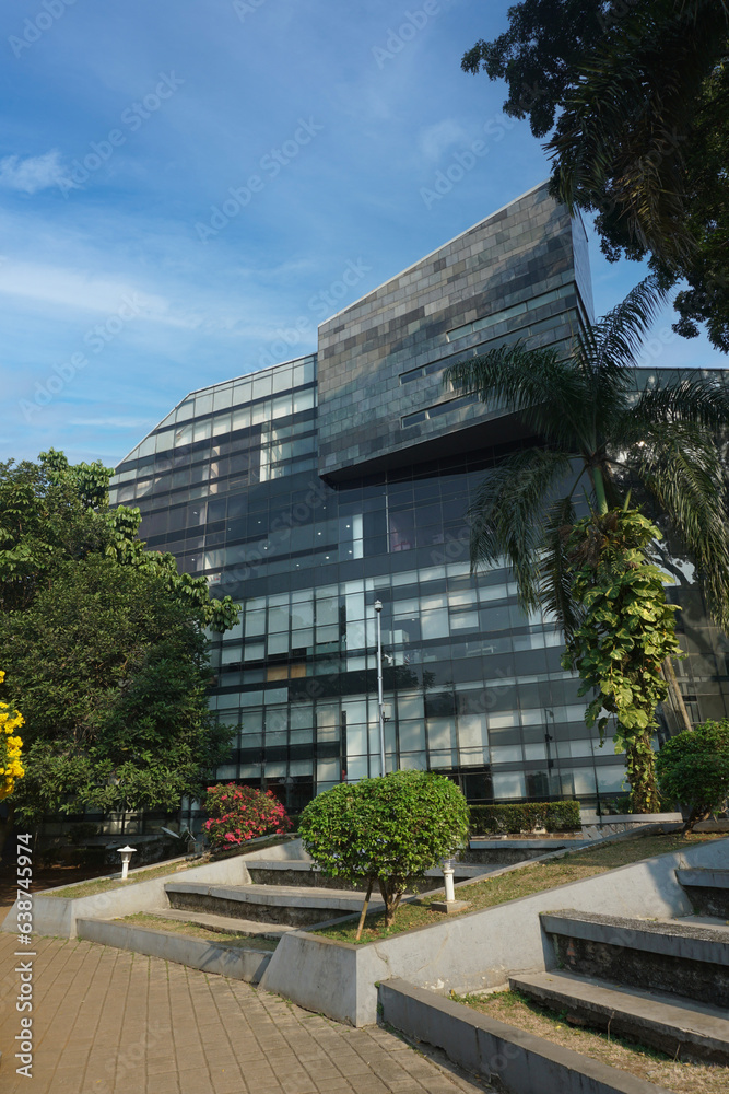 Modern eco-friendly glass architecture and greens against blue sky.