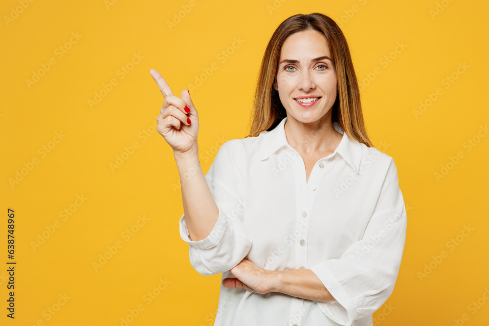 Young happy woman she wearing white shirt casual clothes point index finger aside indicate on workspace area copy space mock up isolated on plain yellow background studio portrait. Lifestyle concept. Young happy woman she wearing white shirt casual clothes point index finger aside indicate on workspace area copy space mock up isolated on plain yellow background studio portrait. Lifestyle concept.
