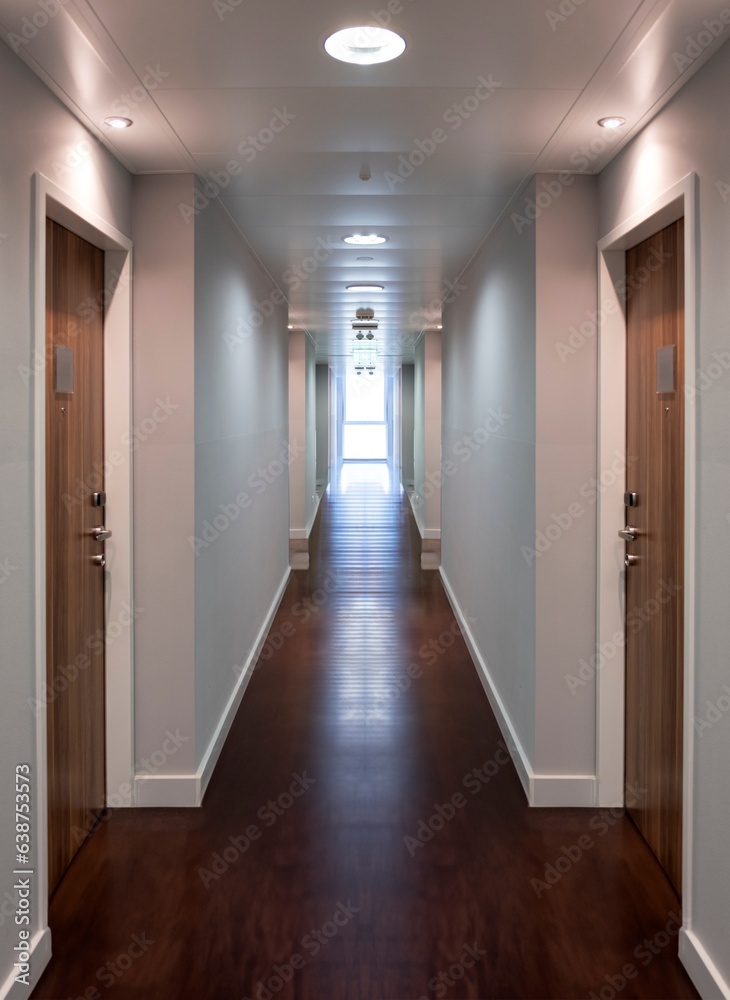 Empty illuminated hotel, office corridor with wooden floor. Hallway with wood closed door.