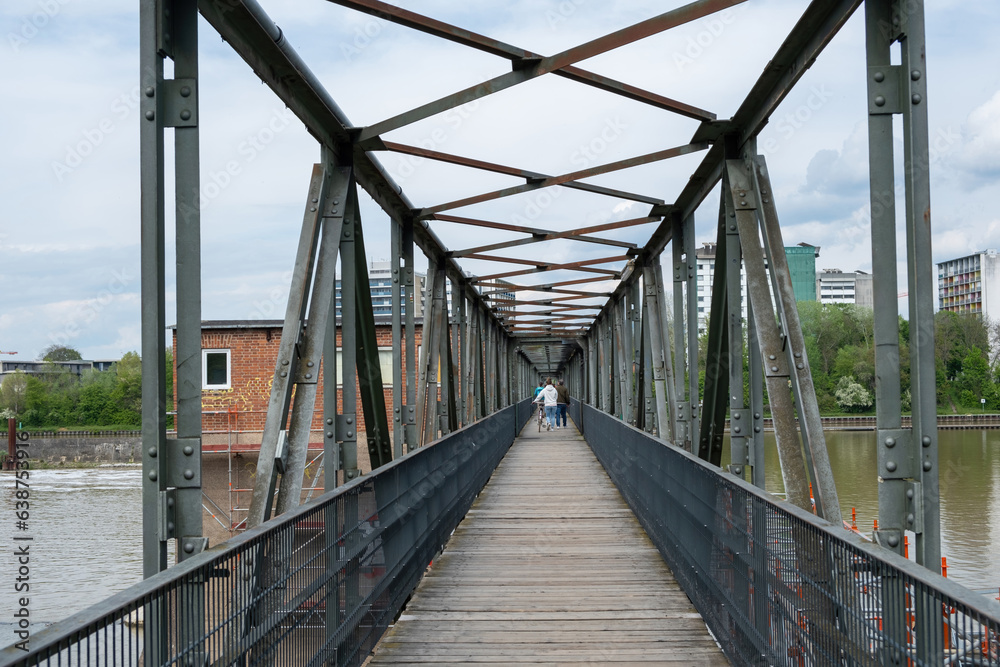 Metal pattern bridge over Neckar River, people crossing the footbridge at Heidelberg city, Germany.