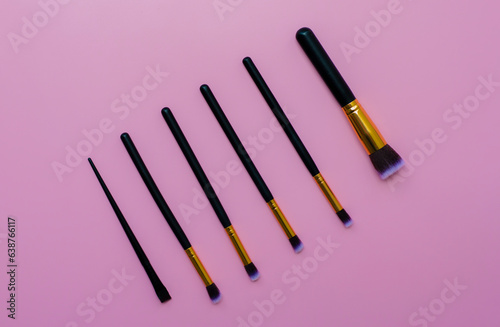 set makeup brushes on pink or purple colored composed background. Top view