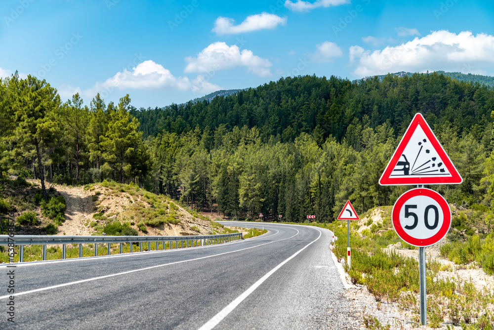 50 km/h speed limit and warning signs on the winding asphalt road going ...