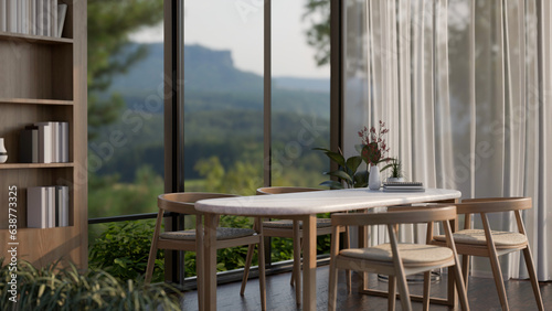 A dining table in a modern dining room with a large window with an amazing mountain view.