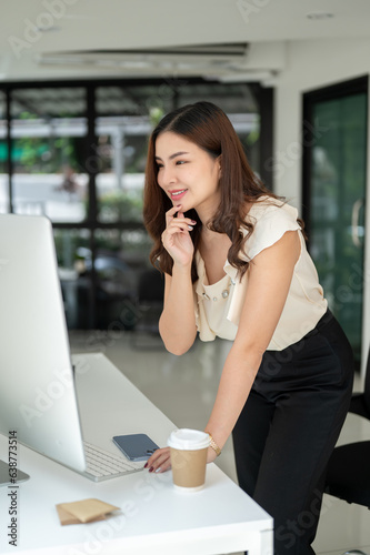 A gorgeous Asian businesswoman bending over a table to check her project on a computer