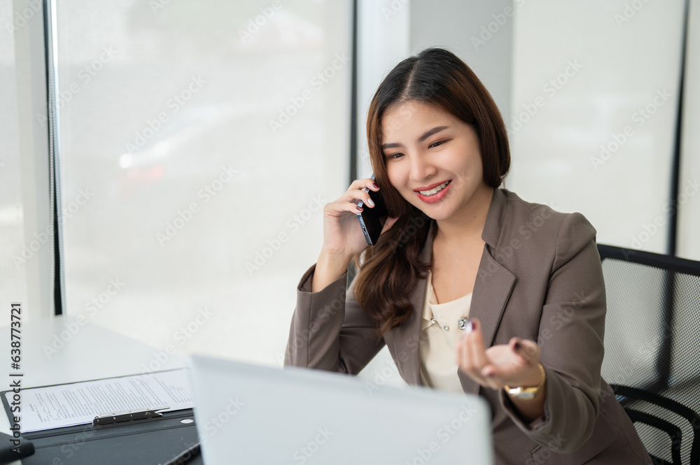 A cheerful Asian businesswoman is talking on the phone A cheerful Asian businesswoman is talking on the phone