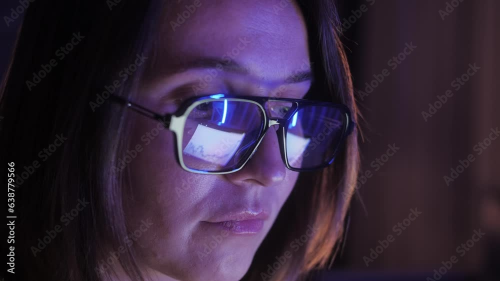 Businesswoman working at night looking at monitor, reflections in eyeglasses. Person stock market trader using laptop at office or home office. Business concept. Distance work. Businesswoman working at night looking at monitor, reflections in eyeglasses. Person stock market trader using laptop at office or home office. Business concept. Distance work.