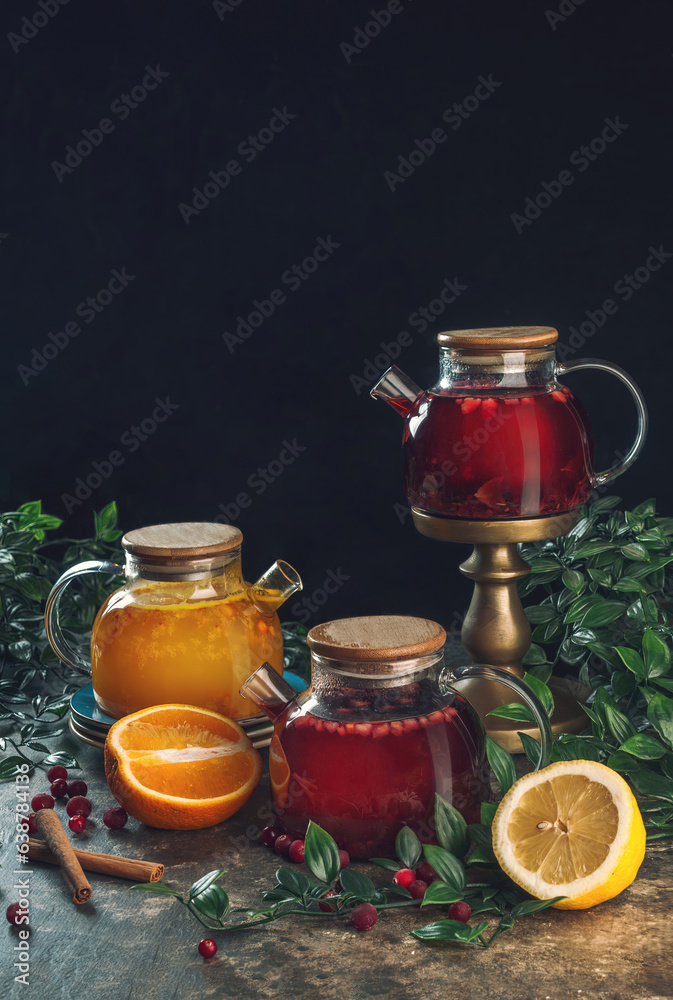 various teapots with herbal and fruit tea on black background. various teapots with herbal and fruit tea on black background.