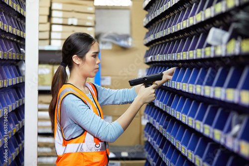 factory worker using laser barcode scanner and looking spare parts storage cabinet