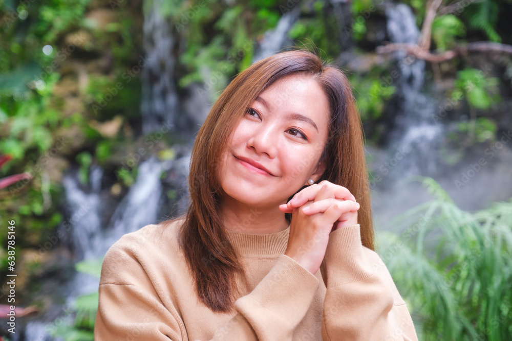 Portrait image of a young woman holding hands and relaxing in the garden Portrait image of a young woman holding hands and relaxing in the garden