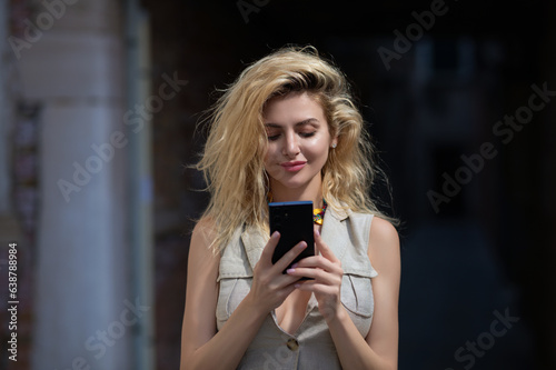 Portrait of blonde woman with mobile phone. Pretty girl talk by mobile cell phone. Call on phone outdoor. Millennial lady talk phone outsite in city. Woman hold mobile cellphone, chatting phones. photo