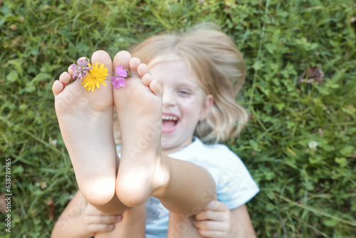 Fotografija Child feet on green grass, barefoot little girl on meadow, countryside lifestyle