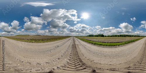 360 hdri panorama on wet gravel road with marks from car or tractor tires with clouds on blue sky in equirectangular spherical seamless projection, skydome replacement in drone panoramas