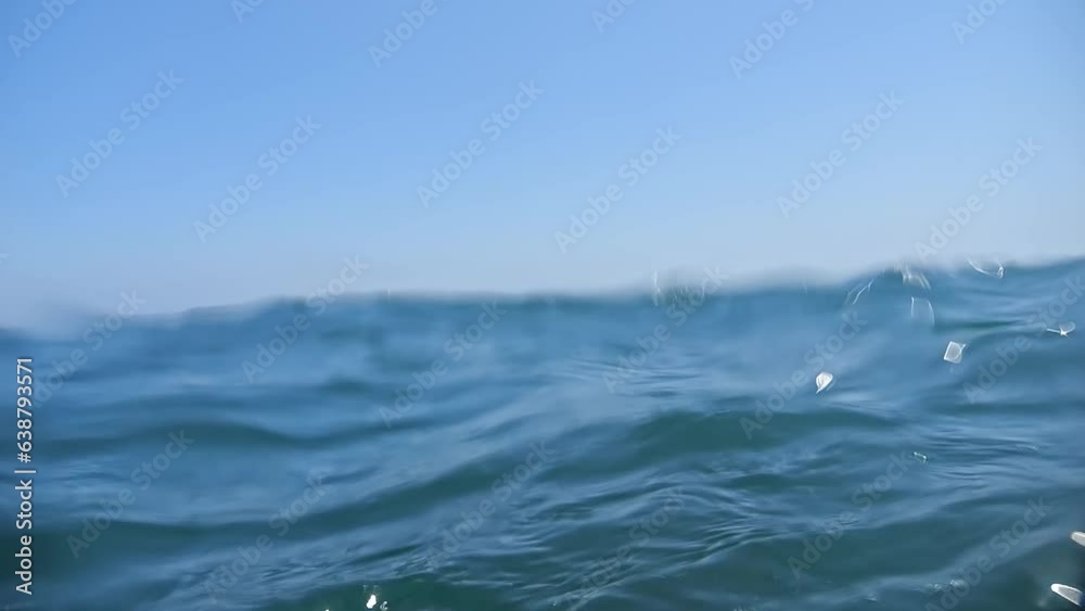 Under and over the sea: a slow-motion dive and emergence amidst gentle waves on a sunny day.