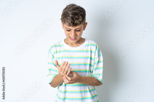 Beautiful kid boy wearing striped casual t-shirt Suffering pain on hands and fingers, arthritis inflammation