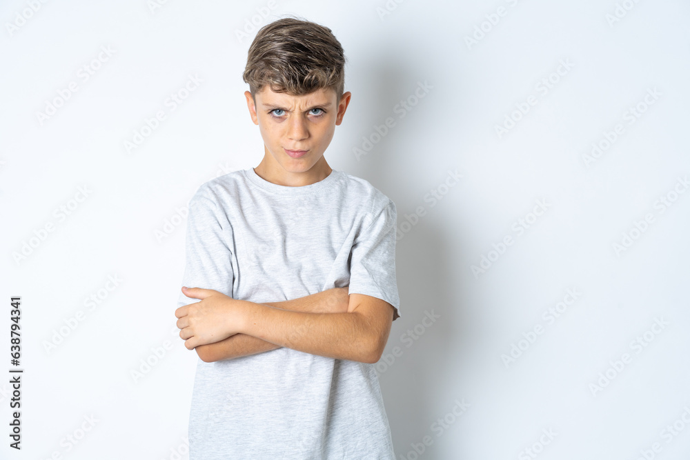 Gloomy dissatisfied Beautiful kid boy wearing grey casual t-shirt looks with miserable expression at camera from under forehead, makes unhappy grimace Gloomy dissatisfied Beautiful kid boy wearing grey casual t-shirt looks with miserable expression at camera from under forehead, makes unhappy grimace