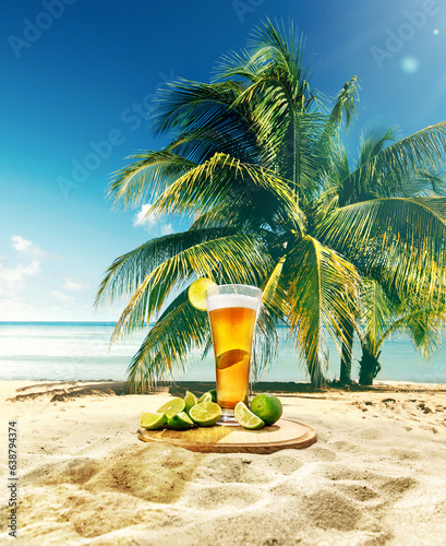 Glass with delicious lager beer with lime appetizers on sand near palm with blue sky and ocean background. Concept of beer, brewery, holidays and vacation, traditions, festival, alcohol drink, ad photo