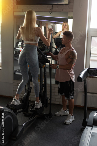 Beautiful slim fitness girl and handsome muscular trainer man training in the gym and doing cardio exercise in the sport gym