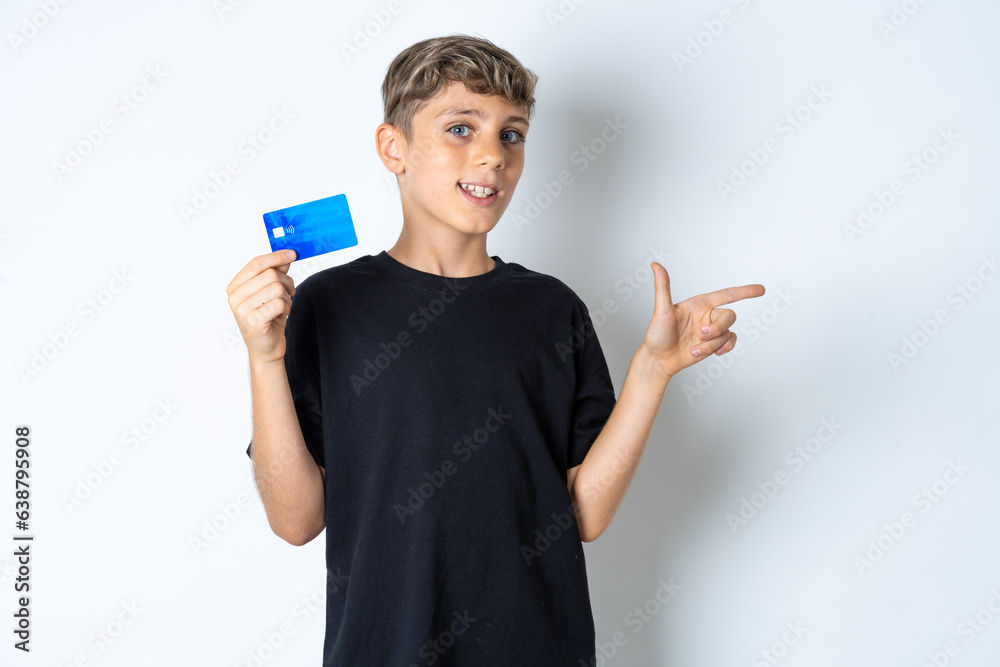 Curious smiling Beautiful kid boy wearing black casual t-shirt showing plastic bank showing finger copyspace Curious smiling Beautiful kid boy wearing black casual t-shirt showing plastic bank showing finger copyspace
