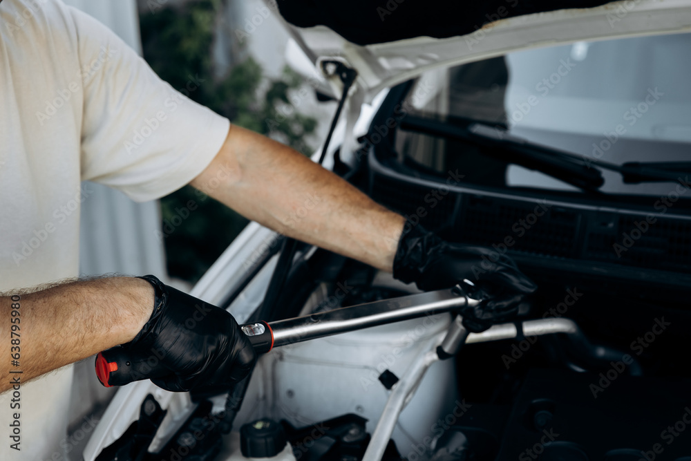 The man holds socket head for a wrench for tightening and unrolling nuts and bolts. A set of adapters. Work in a car repair shop, service, garage. The man holds socket head for a wrench for tightening and unrolling nuts and bolts. A set of adapters. Work in a car repair shop, service, garage.