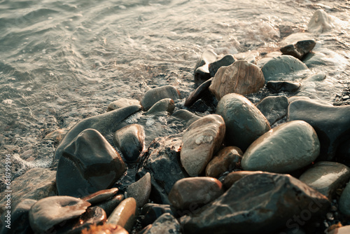 The sea at sunset washes the beach of small stones.