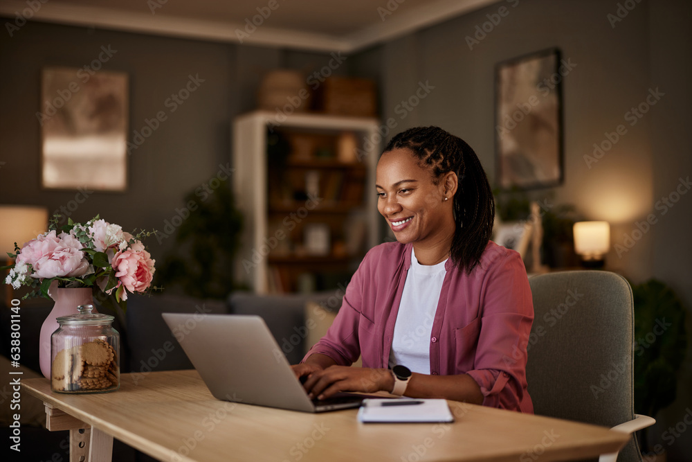 A smiling African female freelancer typing on a laptop at the home office. A smiling African female freelancer typing on a laptop at the home office.
