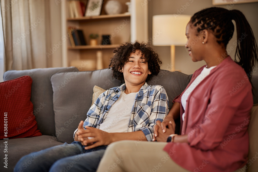 A smiling teenage boy sitting on the couch with his mother, making jokes. A smiling teenage boy sitting on the couch with his mother, making jokes.