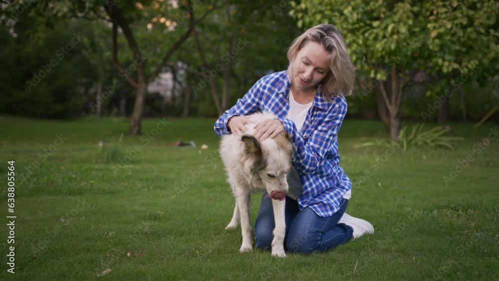 Young woman in the garden with her dog. The owner loves her pet and is happy to spend time with him Young woman in the garden with her dog. The owner loves her pet and is happy to spend time with him