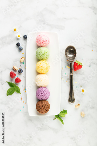 Set of various ice cream scoops and ingredients on white marble background, top view